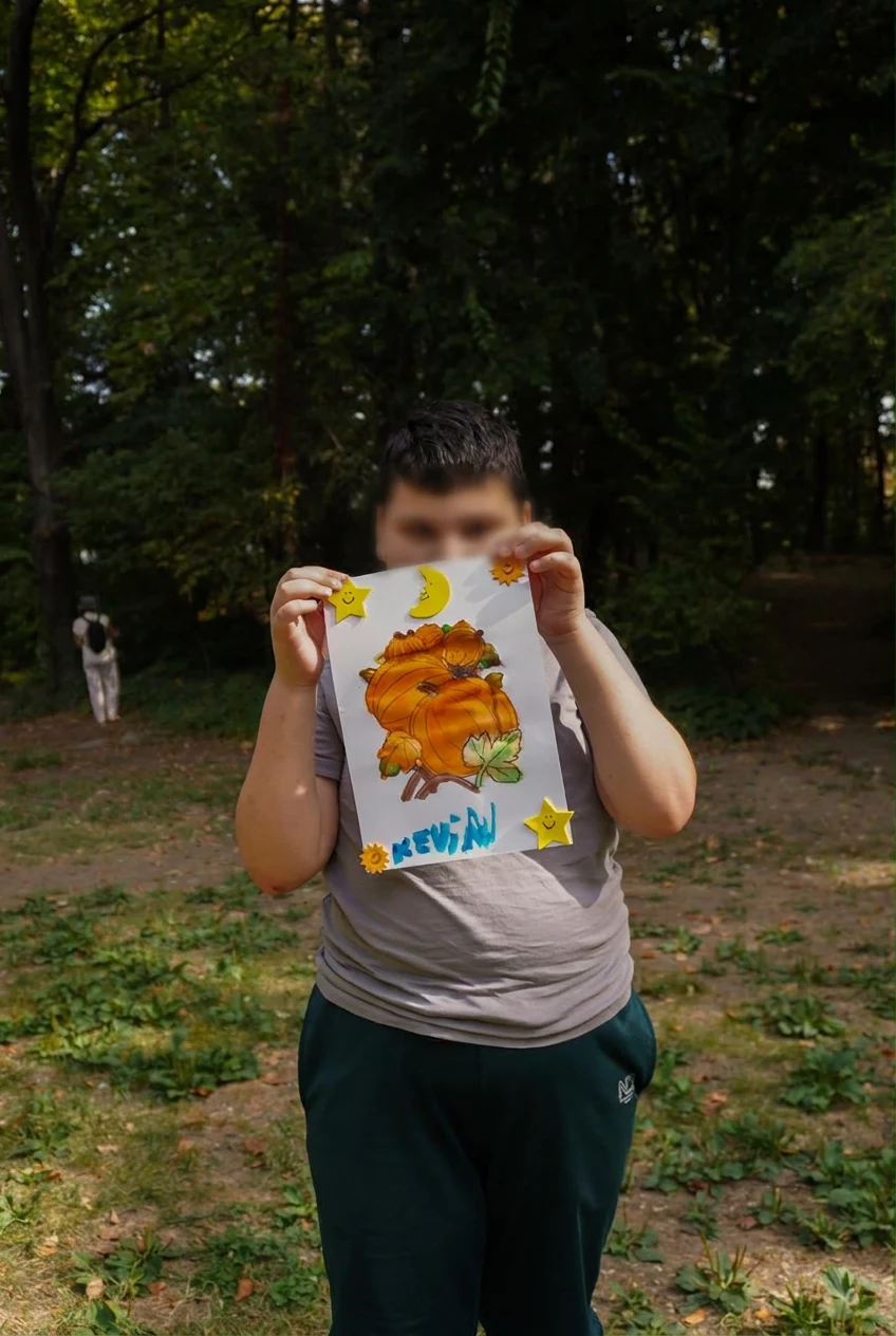 Un copil ține lucrarea cu dovleci, stele și lună
